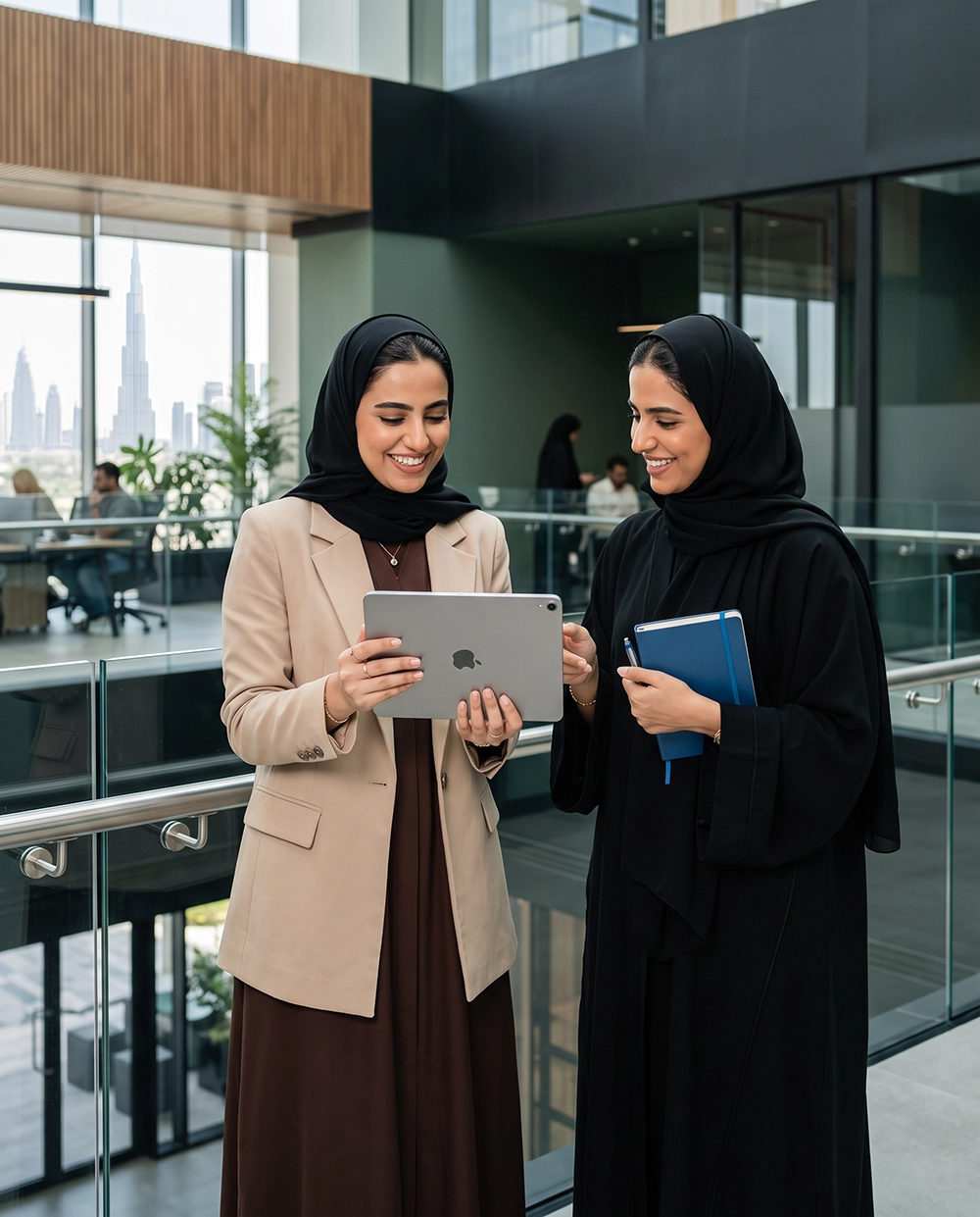 Two smiling Emirati businesswomen discussing financial strategies in an office, illustrating practical saving tips for women.